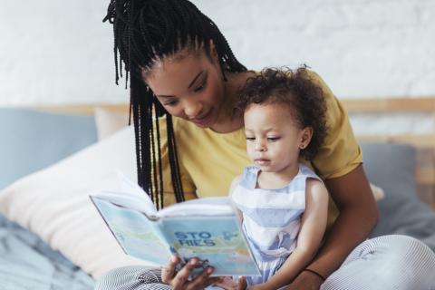 mother and daughter reading on bed