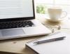 Laptop on desk with pen and cup of coffee