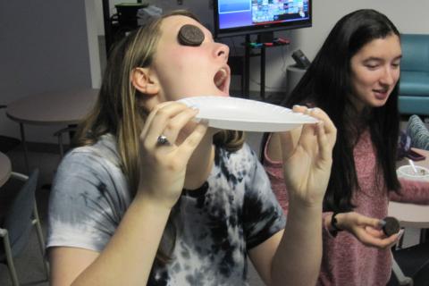 teen girl holding a plate with a sandwich cookie on her face