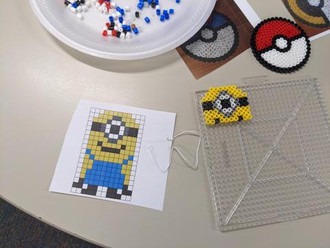 Minion design, partially made Perler bead Minion, loose Perler beads, and Pokeball Perler bead