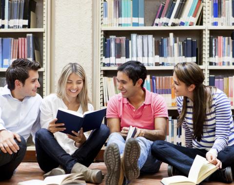 A group of adults sitting and talking on the floor in a library