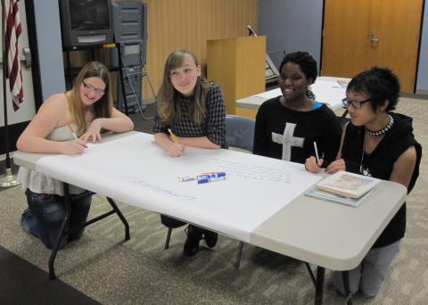 4 teens at a table writing poetry