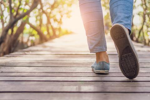 Woman walking on a small wood bridge to nature walk way