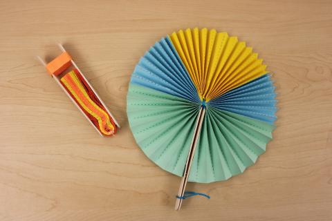 two multicolor paper hand fans. One is folded and was is fully open.