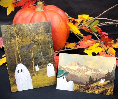 A pumpkin and fall leaves behind two painting prints with added cartoon ghosts