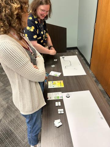 A couple people operating Ozobots on paper.