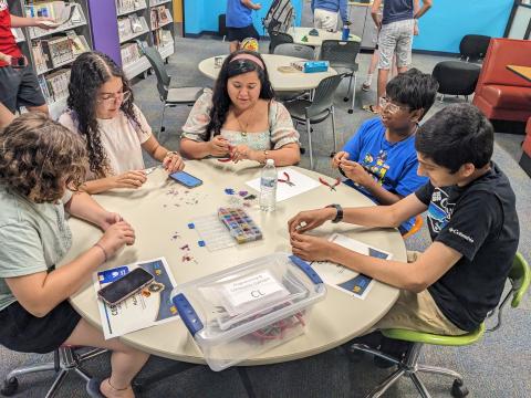 Teens sitting at a round table crafting together.