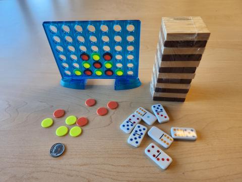 Tiny Connect 4, tiny Jenga, and tiny dominoes games on table with a dime for comparison.