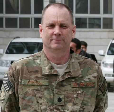 Older adult man wearing camouflage uniform faces forward