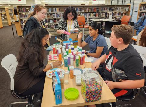 Five teens sort Perler beads at a table.