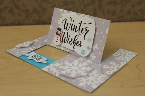 winter themed pop up greeting card. Winter wishes text, snowman, snowflakes, and new year text on the card.