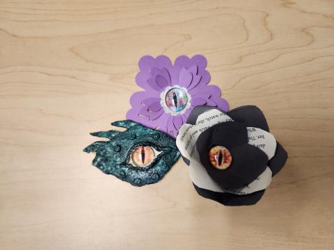 Sample of clay dragon eye painted green with two different samples of paper flowers with dragon eye centers.