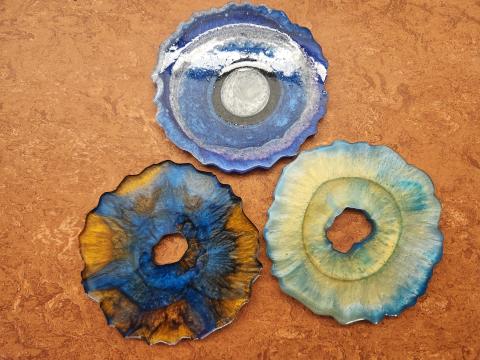 Sample of three geode-shaped resin coasters in blue-white-purple-black rings, dark blue and dark yellow colors, and pastel gold and turquoise colors.