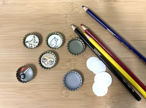 bottle cap charms with Pokeball image, surprised Pikachu, sloth face, and cat, blank bottle caps, circle cutouts, colored pencils