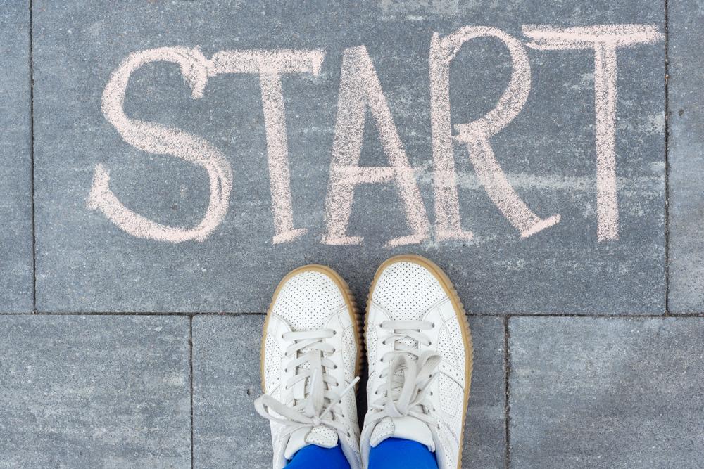 Youth's sneakers standing at the word start written in sidewalk chalk