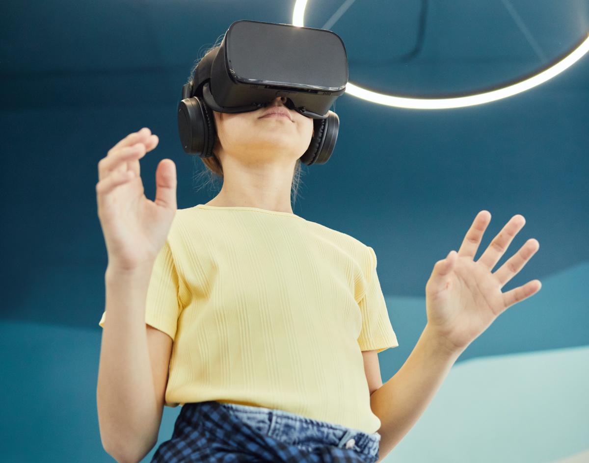 girl in yellow top wearing a black virtual reality headset