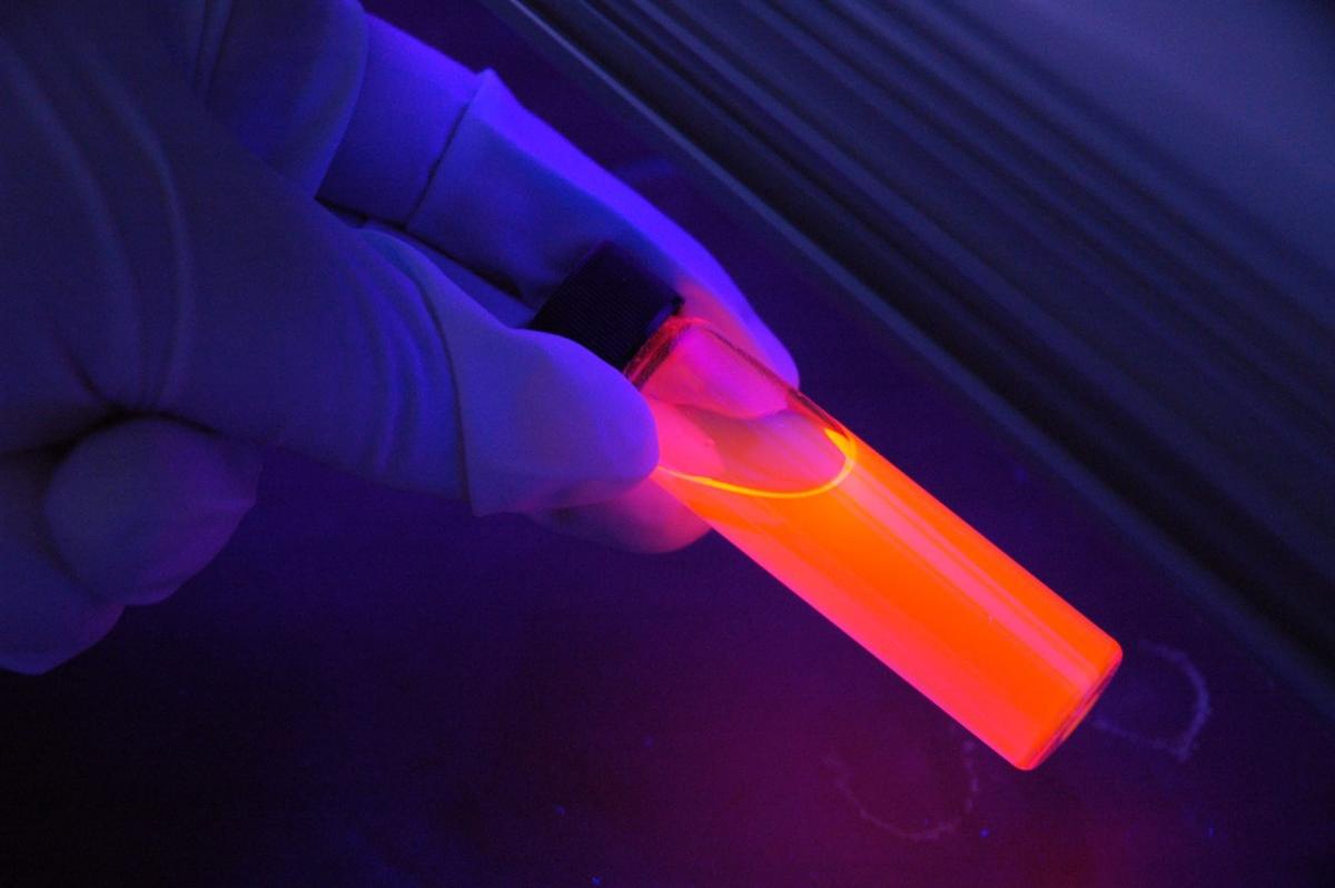 glowing orange test tube held in a gloved hand