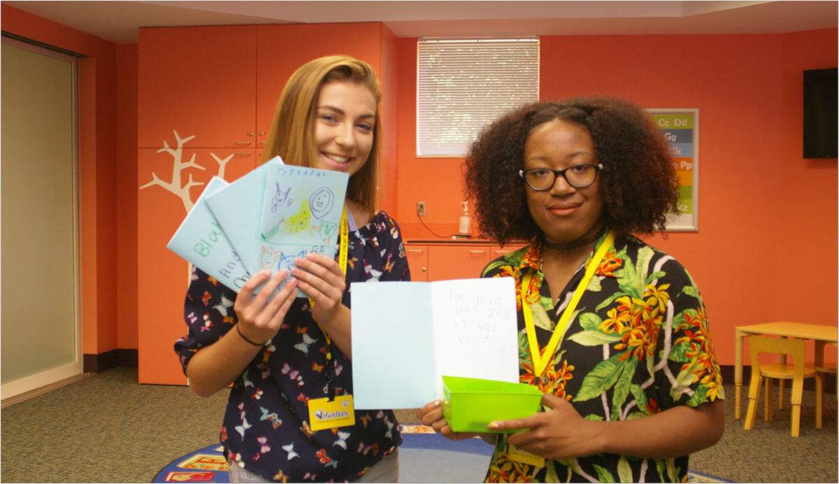 Two young adults holding up journals.