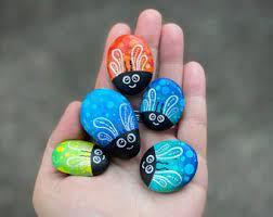 hand holding painted rocks simulating fish and ladybugs