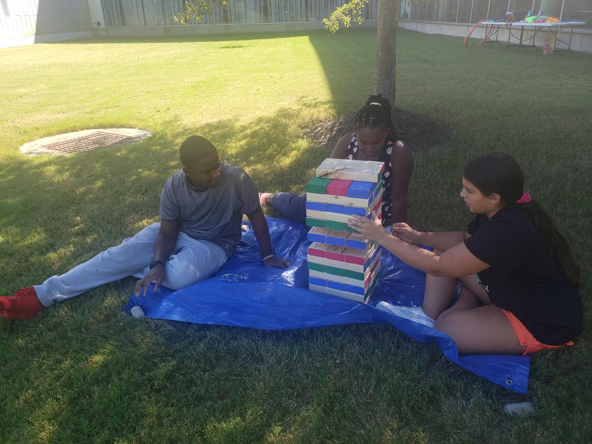 Couple of teens playing jumbo Jenga on the grass