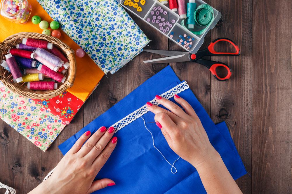 Hands sewing lace onto fabric