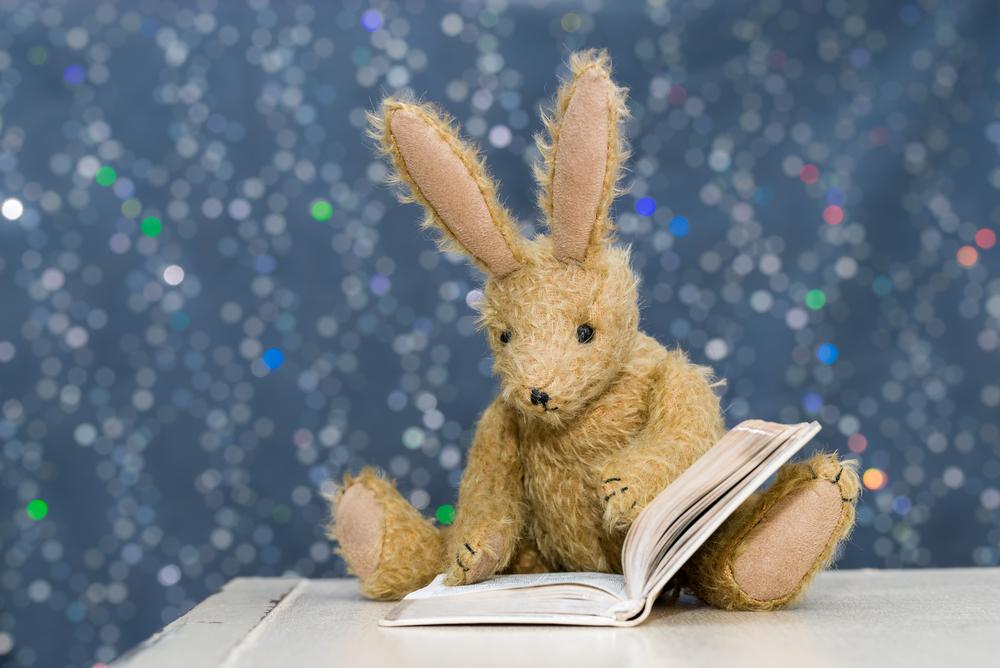 Brown stuffed bunny reading a book