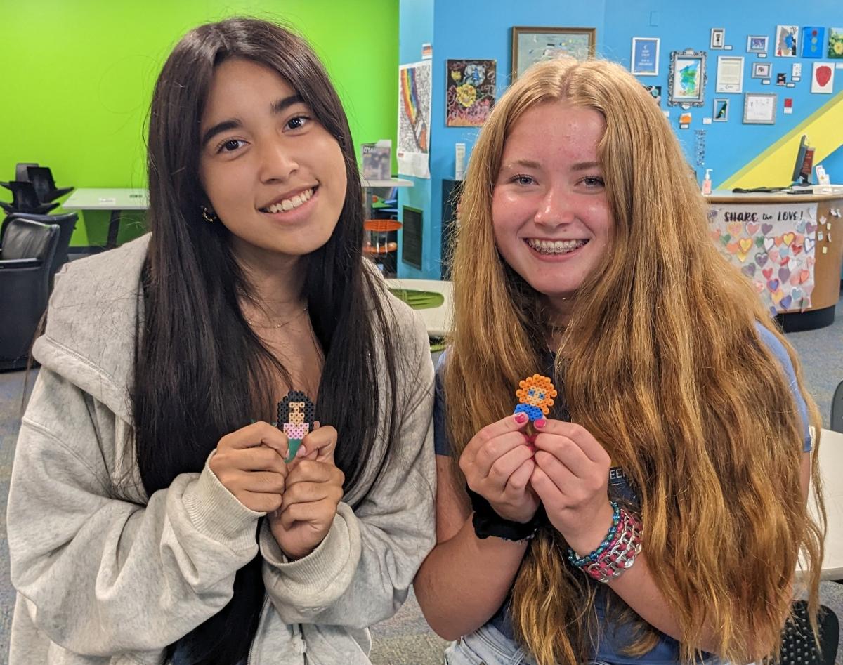 Two teen girls holding their mini Perler Bead creations.