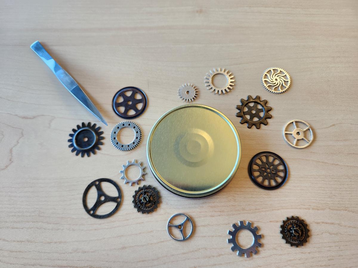 Scattering of clockwork gears and metal lid to use in resin project.