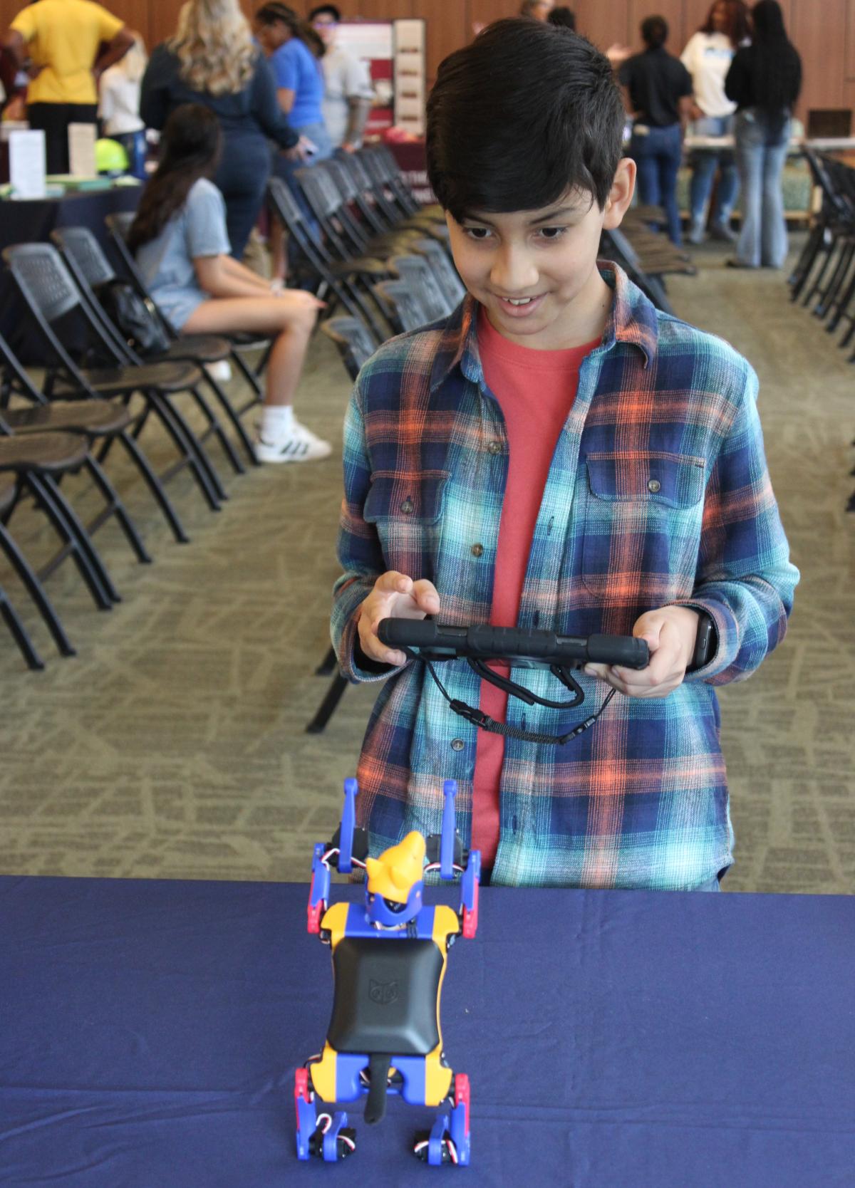 Boy in checkered shirt using an iPad to make Petoi robot dog move.