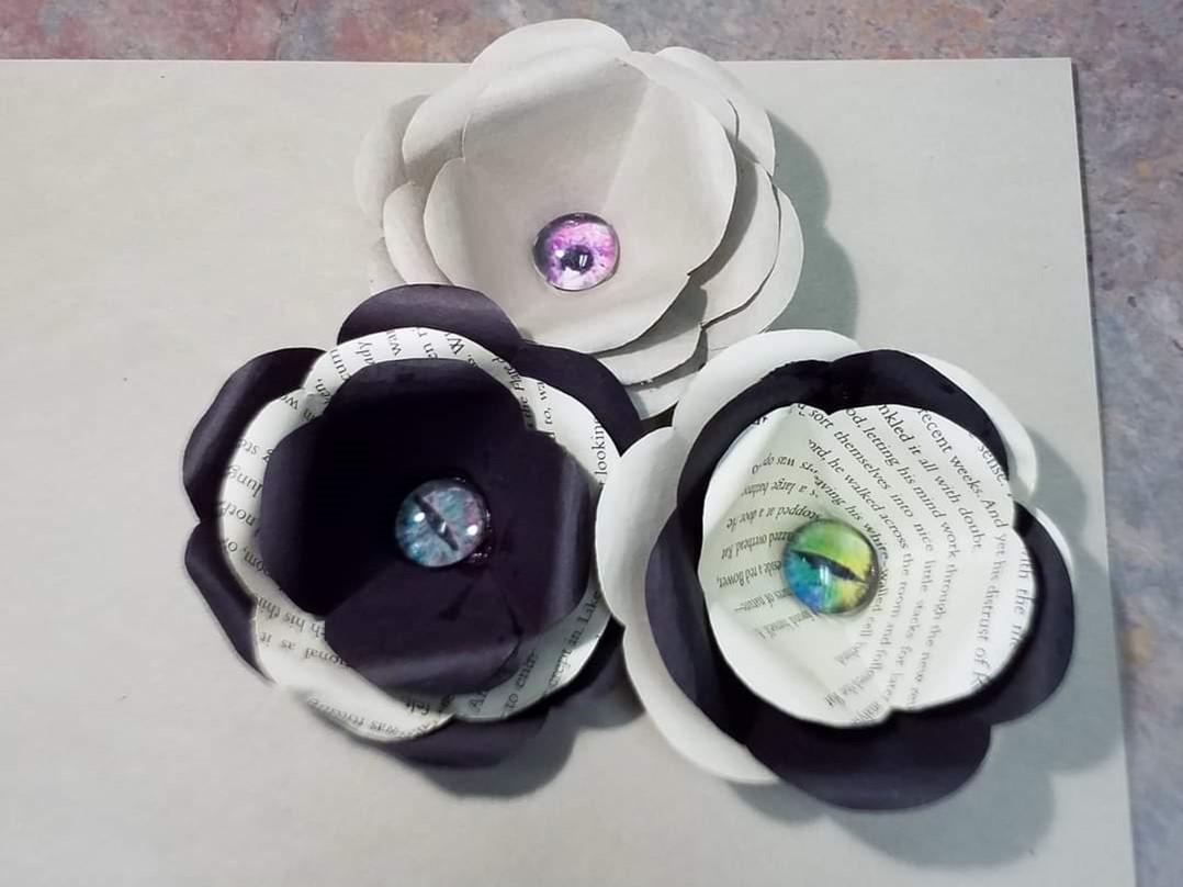 Flowers made of black and white paper with a glass eye in the center.