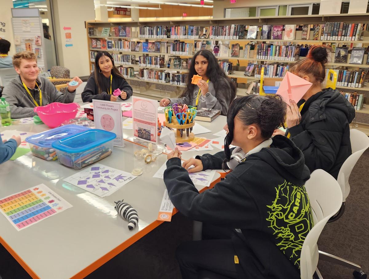 Group of teens around a table making origami flowers