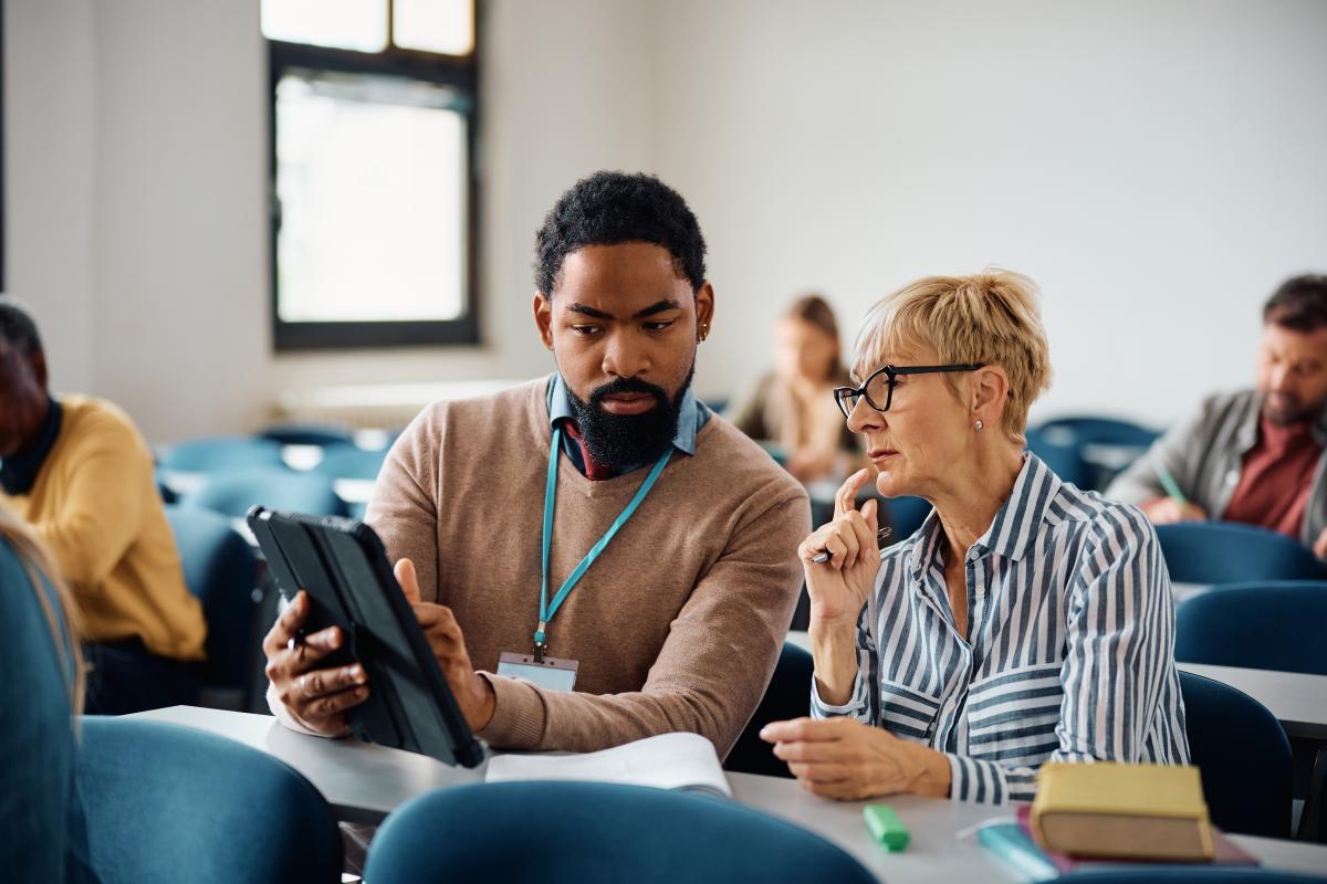 teacher and adult student with tablet