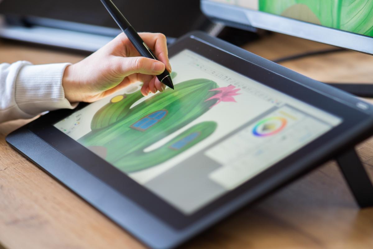 person drawing using stylus and tablet