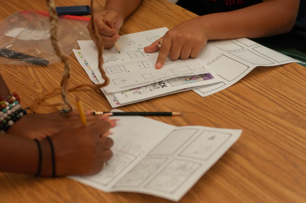 hands working on comics worksheet on table